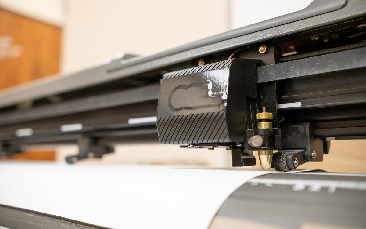 A cutting plotter trimming a sheet of printed vinyl decals