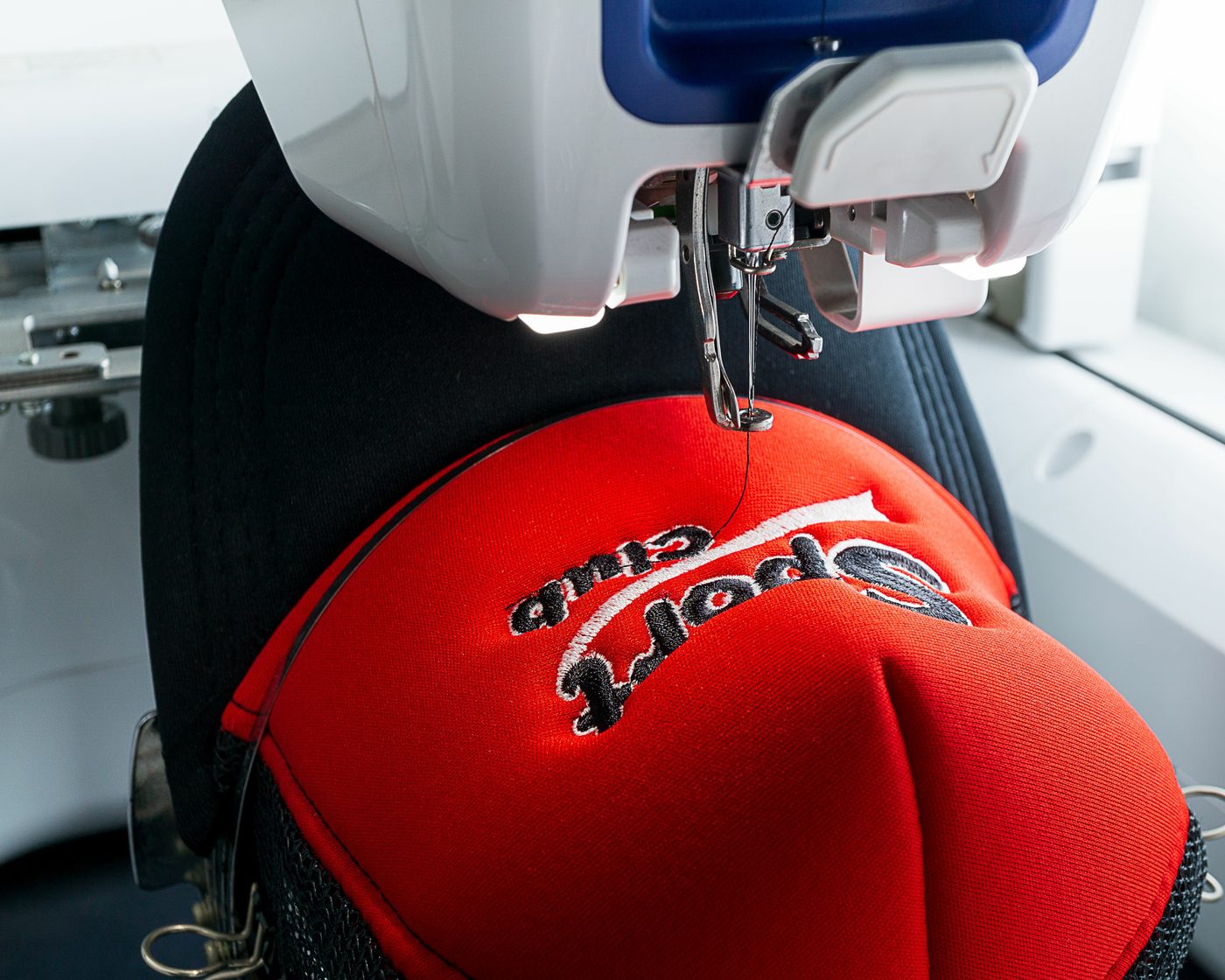 An embroidery machine stitching a logo onto a branded cap